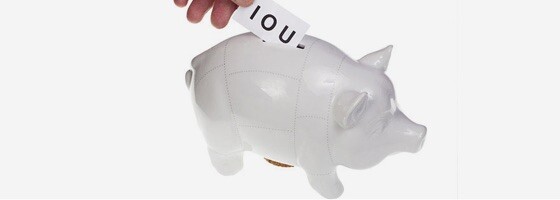 IOU note being slid into a piggy bank