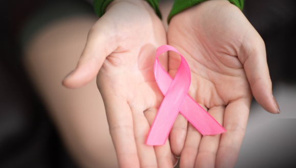A lady holding a pink ribbon in her palms