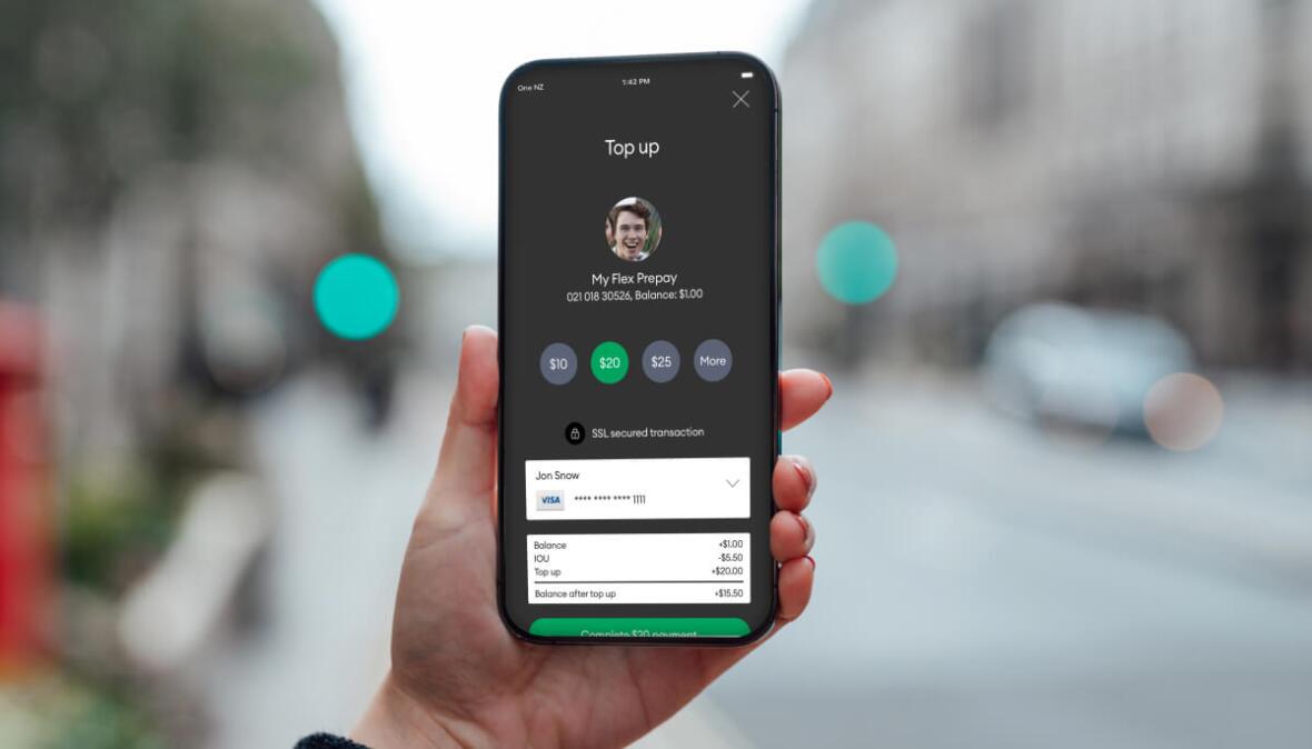 Hand holding a phone to top up their plan