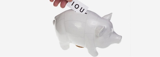 IOU note being slid into a piggy bank