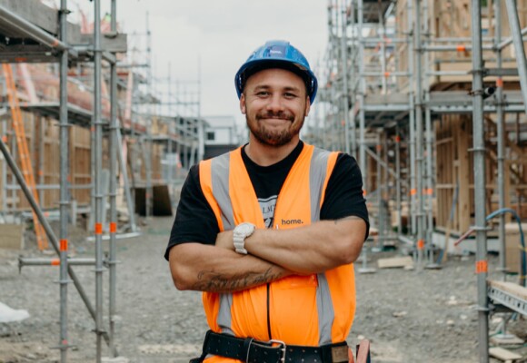 Man in a construction site looking towards camera and smiling