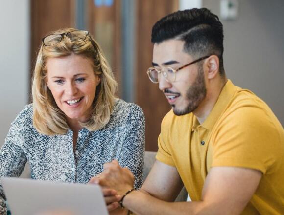 Two people looking at computer screen with smiling faces