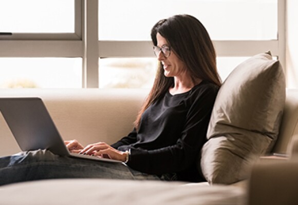 Woman sitting on couch working on a laptop