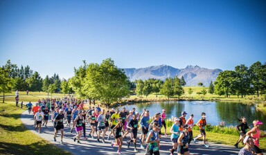 A group of people running marathon on a road near water.
