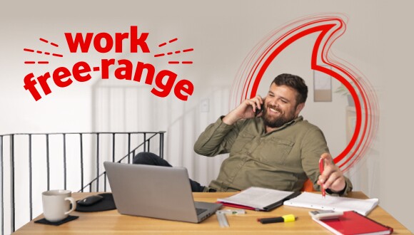 Work Free Range. Man using his laptop and talking on phone in his home office.