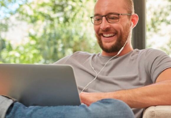 Man working on a laptop wearing earphones