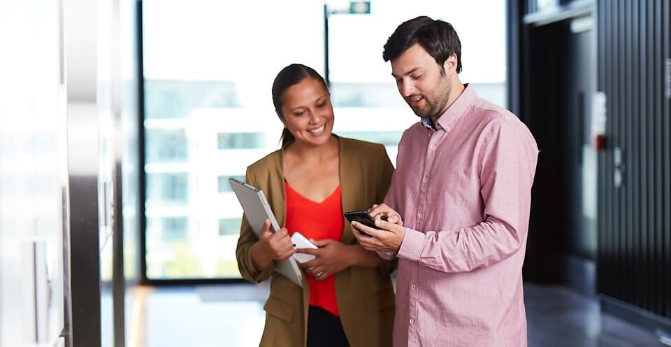 Man showing his mobile phone to a woman in office