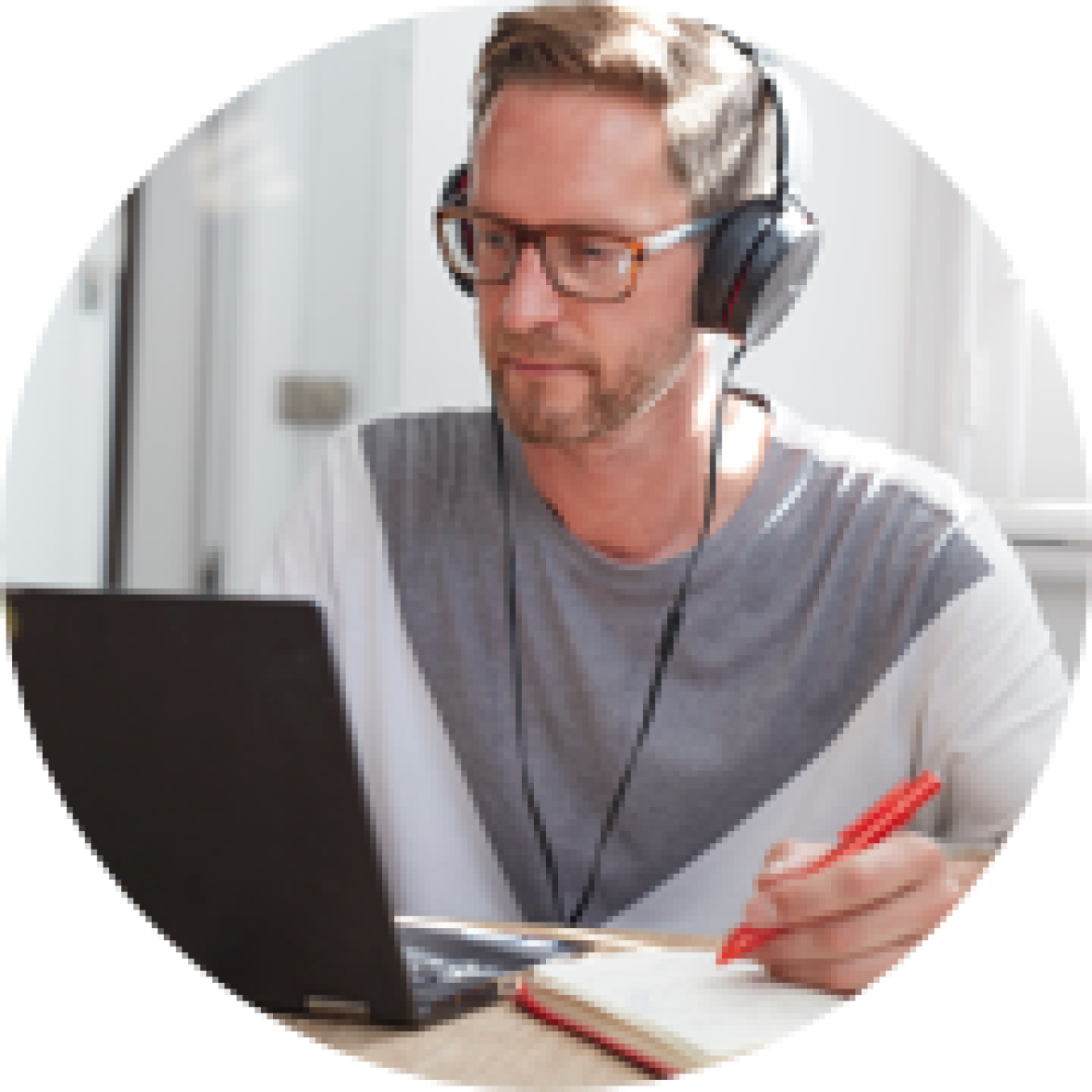 Image of person with headphones on writing in a notepad