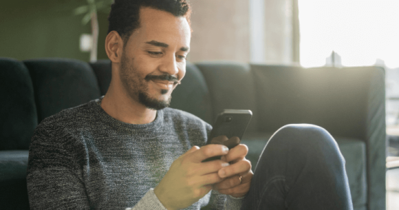 A young man, looking through daily deals on his phone.