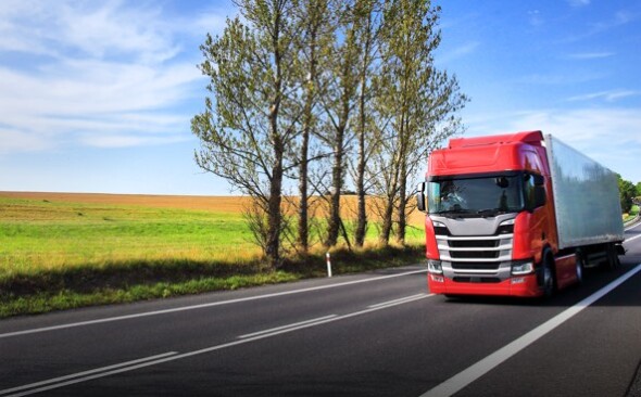red truck on a highway surrounded by pasture lands