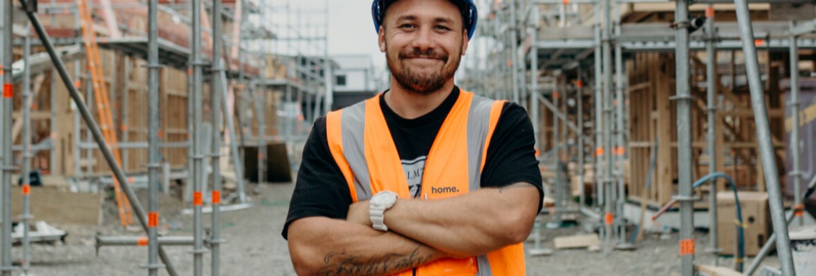 Man in a construction site looking towards camera and smiling