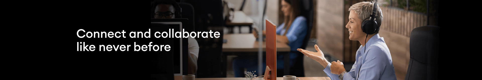I.C.T. at work - a smiling woman at her office desk, with headphones on.
