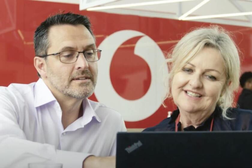 A man and woman talking in front of a laptop at a Vodafone Store