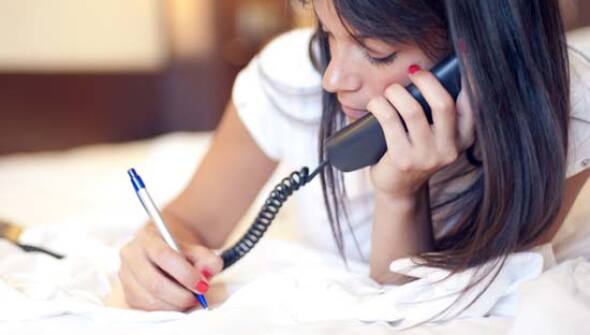 Woman talking on the phone and writing on paper.