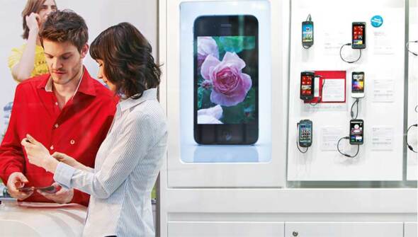 A man and a woman in a Vodafone retail store looking at a mobile phone