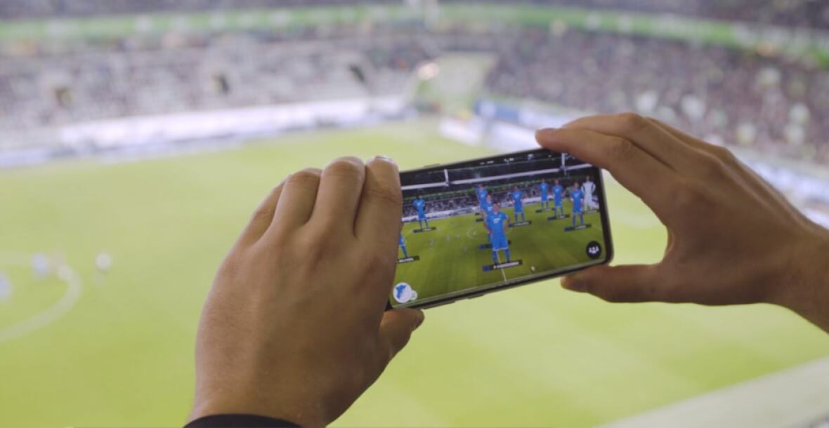 Person holding mobile phone in a stadium