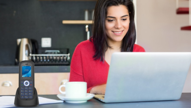 woman in red smiling and typing on her laptop