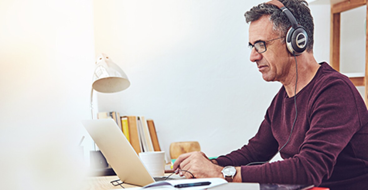 Man working on a laptop wearing a headphone
