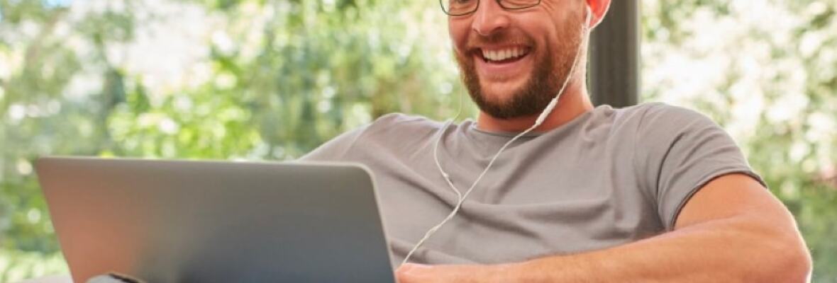 Man working on a laptop wearing earphones