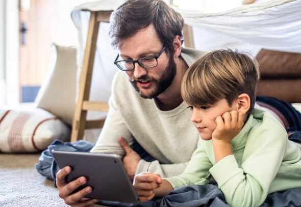 A father and son, looking at an iPad together.