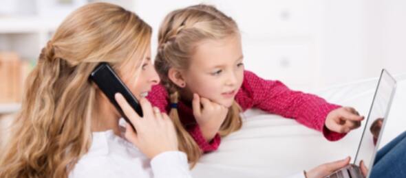 Person on phone and child pointing at the computer screen