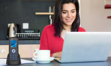 woman in red smiling and typing on her laptop