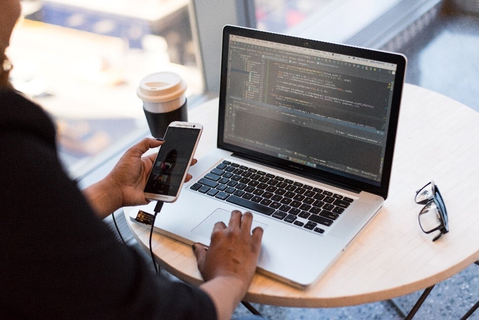 women in cafe using laptop and phone with coffee and glasses on table