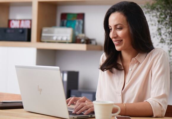 Woman working on laptop with coffee cup on table