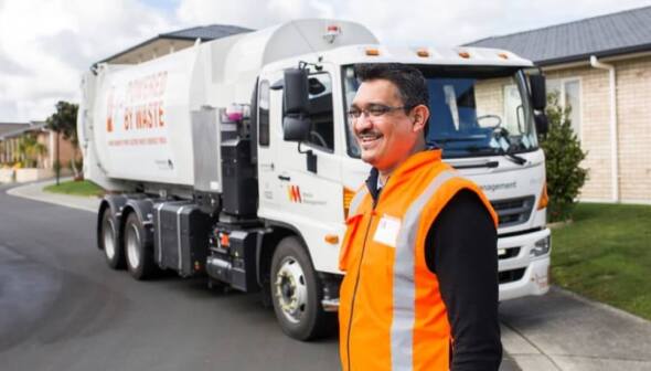 Waste Management worker in front of the work truck
