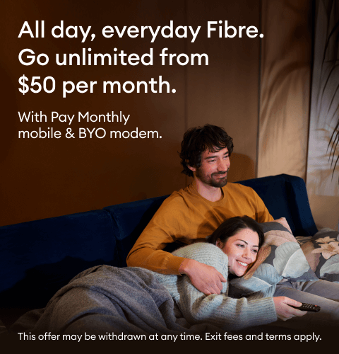 A couple snuggling on a couch, watching TV over fibre broadband.