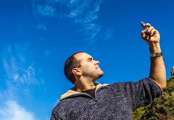 A man holds up his mobile phone to check for signal.