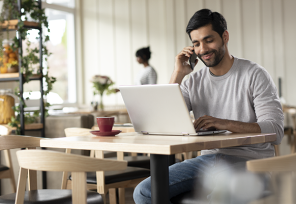 Man looking at a laptop while talking on the phone