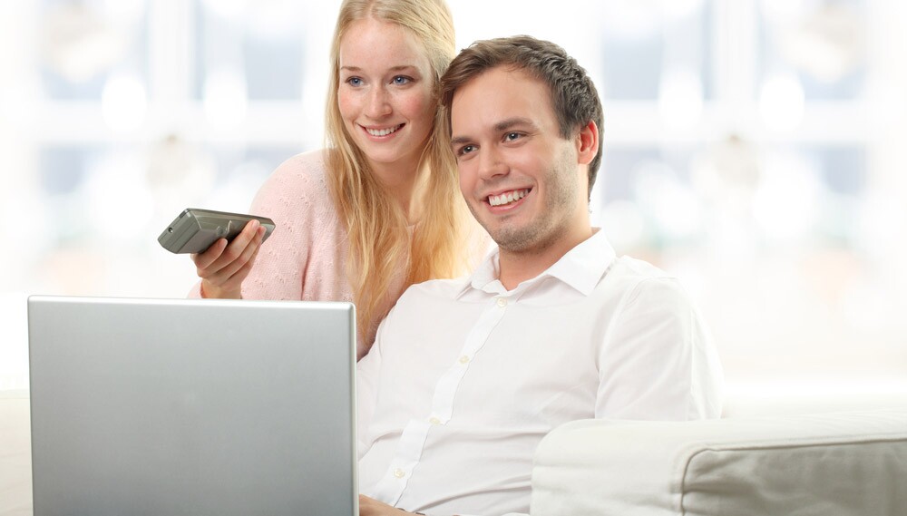 Man and woman watching TV with remote inhand