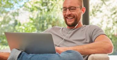 Man working on a laptop wearing earphones