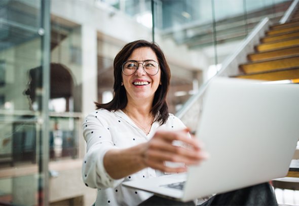 Woman smiling while showing her laptop to others 