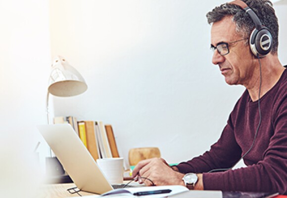 Man working on a laptop wearing a headphone