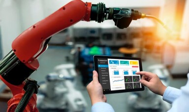 Worker looking at a tablet and machine in a factory