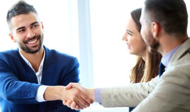 Two men shaking hands and a woman looking at them