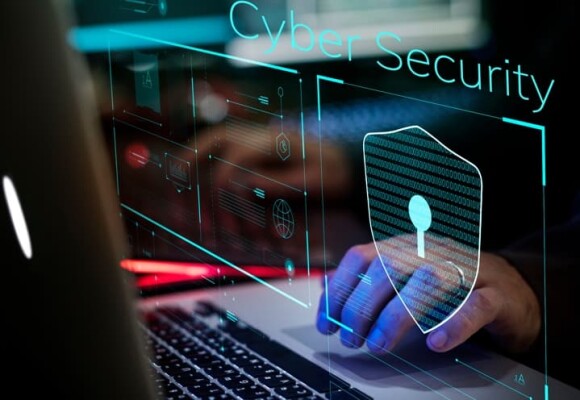 Person working on a laptop showing cyber security logo