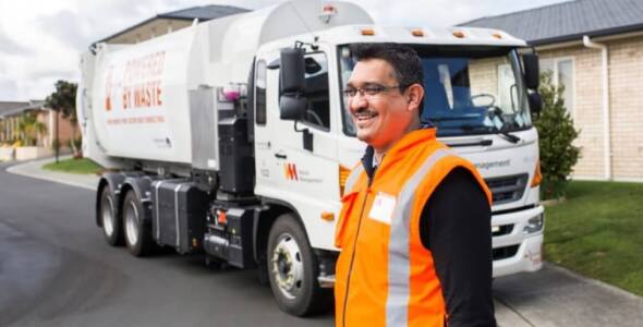 Waste Management worker in front of the work truck
