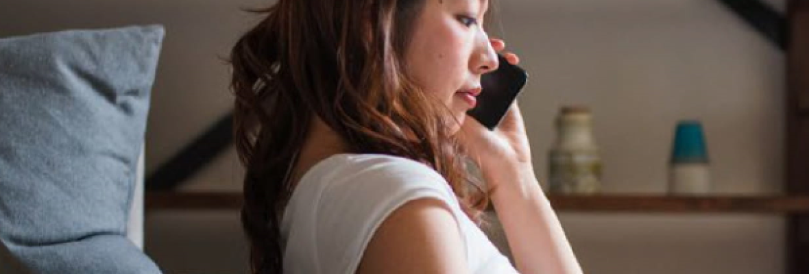 woman talking on phone next to her bed