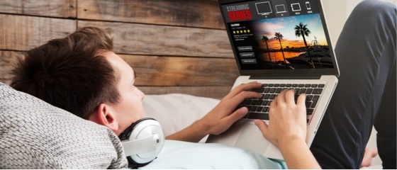 A man lying back on a couch while using his laptop