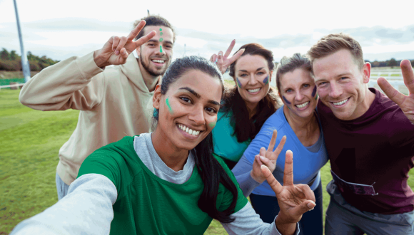 Group of 5 people smile and pose to the camera selfie style.