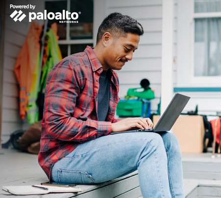 Man sitting outside house working on laptop