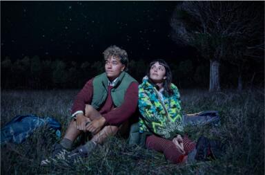 Jade and pippa sitting on grass looking towards sky.