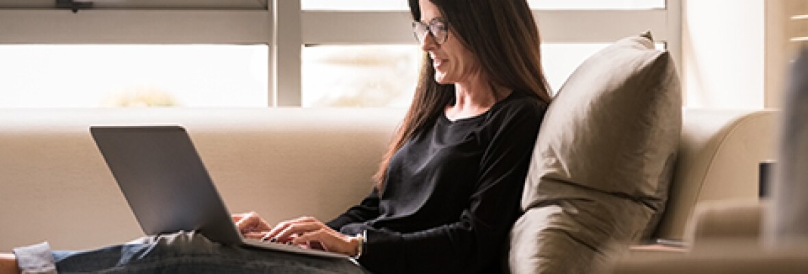 Woman sitting on couch working on a laptop
