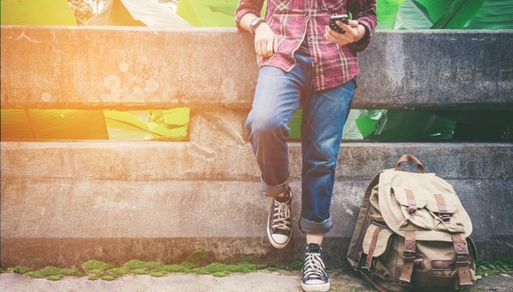 Man looking at his phone with a bag on the ground