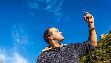 A man holds up his mobile phone to check for signal.