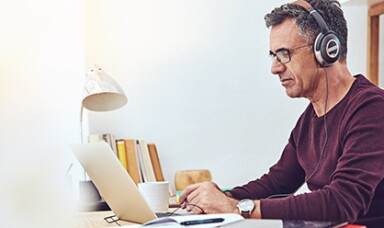 Man working on a laptop wearing a headphone