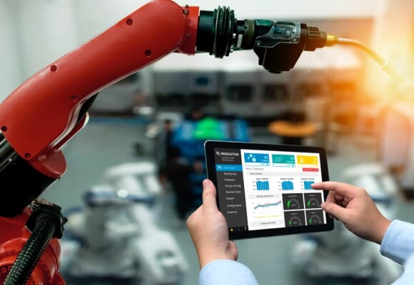 Worker looking at a tablet and machine in a factory